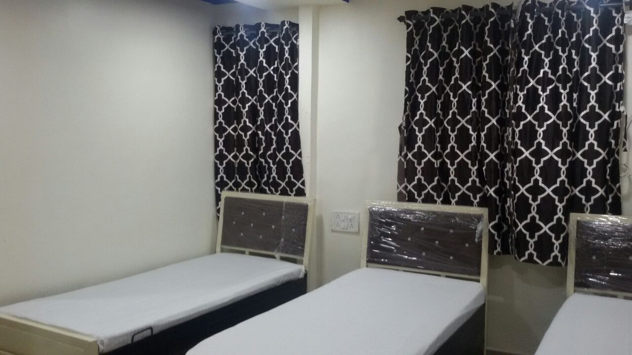 Room with patterned curtains and beds at The Aura