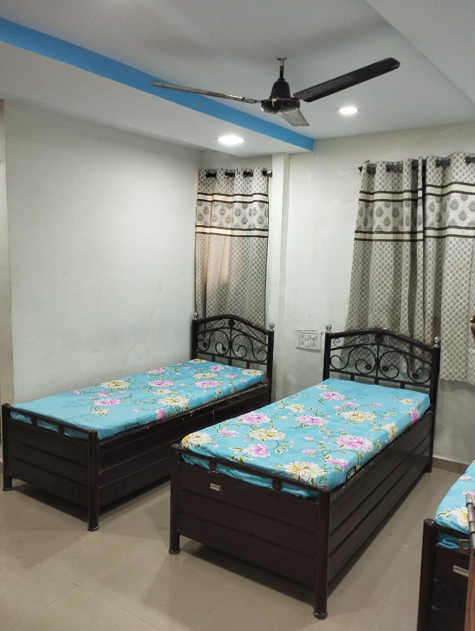 Twin beds with floral bedding and blue accent at The Aura