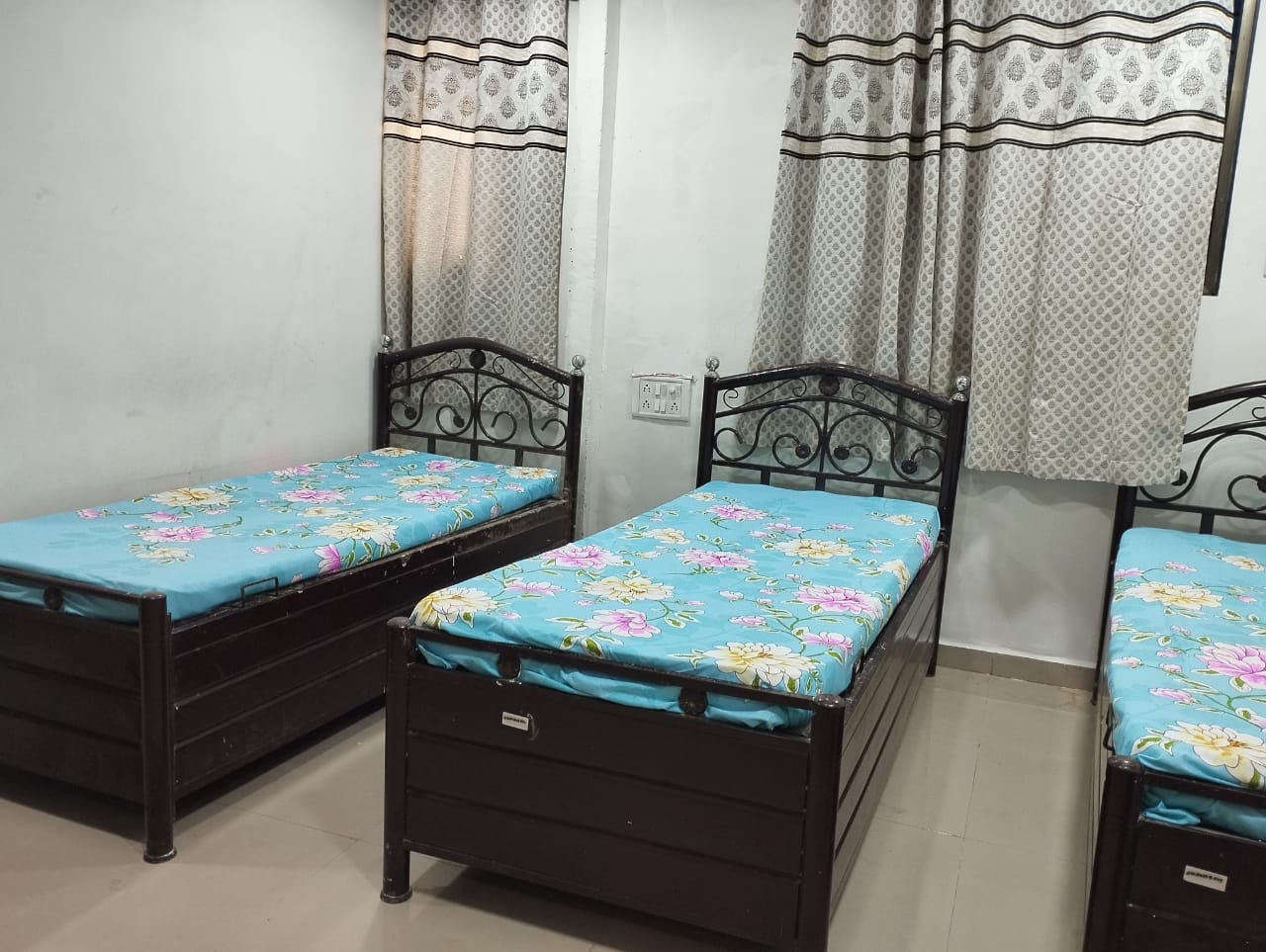 Room with floral bedding and iron bed frames at The Aura